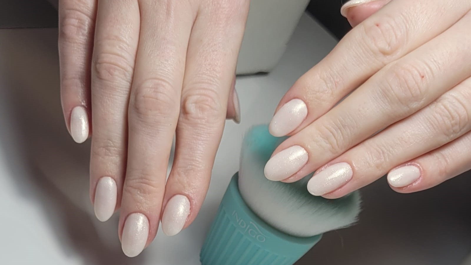 Jasny manicure na dłoniach klientki, zdjęcie bez twarzy